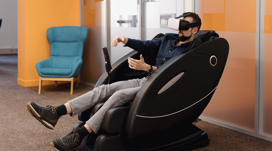 Homme portant un casque de réalité virtuelle dans un fauteuil de massage.