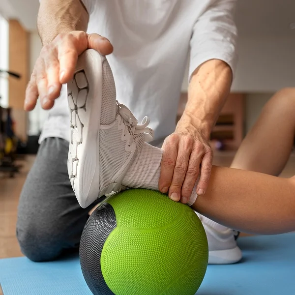 Un homme effectue un exercice de rééducation physique avec un ballon, concentré sur sa posture et son équilibre.